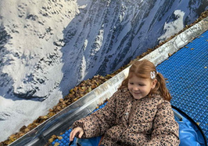 Dziewczynka ślizga się na pontonie na tle zimowej tapety.