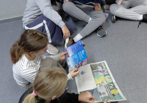 Uczniowie oglądają ulotki i bilety wstępu z miejsc turystycznych.