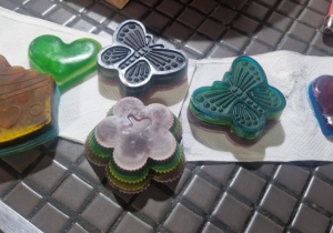 Uczniowie wlewają barwną substancję do formy na mydła.