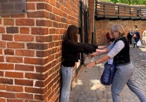 Uczennica próbuje prosto stanąć pod Krzywą Wieżą w Toruniu.