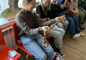 Uczniowie podczas warsztatów w Łódzkim Ogrodzie Zoologicznym trzymają węża zbożowego.