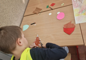 Przedszkolaki wykonują prace plastyczne oparte na jesiennych inspiracjach.