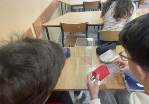 Uczniowie pracują z modelami brył aby lepiej zrozumieć pojęcia geometryczne
