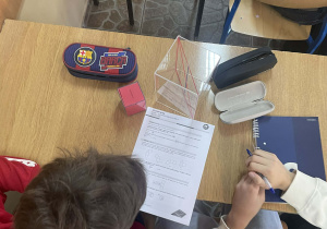 Uczniowie pracują z modelami brył aby lepiej zrozumieć pojęcia geometryczne