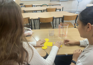 Uczniowie pracują z modelami brył aby lepiej zrozumieć pojęcia geometryczne