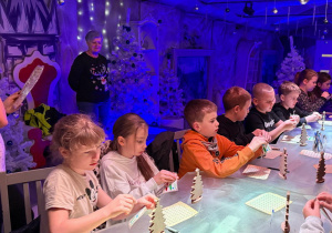 Dzieci wykonują świąteczne prace plastyczne podczas warsztatów.