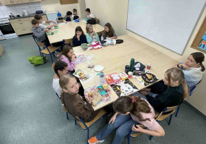 Dzieci z klasy 4a siedzą przy stołach w pracowni kulinarnej. Jedzą przygotowane przez siebie śniadanie podczas lekcji edukacji zdrowotnej