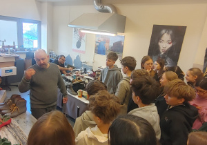 Uczniowie zwiedzają pracownię szewską.