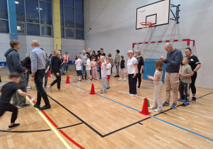 Uczestnicy konkurencji sportowych, w wybranych drużynach czekają na sali gimnastycznej na rozpoczęcie pierwszej konkurencji.