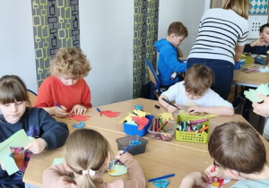 Uczniowie wykonują prace plastyczne – kolorowe ptaszki z rolek po papierze toaletowym.