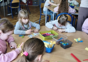 Uczniowie wykonują prace plastyczne – kolorowe ptaszki z rolek po papierze toaletowym.