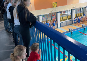Rodzice wraz dziećmi oglądają pokaz umiejętności pływackich uczniów naszej szkoły
