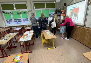 Rodzice z dziećmi podczas zwiedzania szkoły i rozmów z nauczycielami.