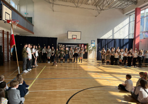 Uczniowie w trakcie występu na uroczystej akademii – harcerze i szkolny chór