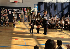 Pani dyrektor podczas uroczystego apelu udziela pochwały dwóm uczennicom za udzielenie pierwszej pomocy przedmedycznej osobie potrzebującej nagłej pomocy.