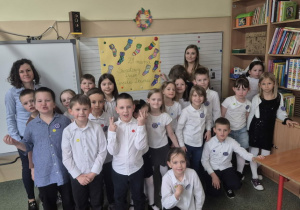 Uczniowie, wraz z Paniami organizującymi Dzień Kolorowej Skarpetki, prezentują wykonany plakat
