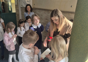 Uczniowie biorą udział w zabawie terenowej, podążając po szkole za wskazówkami.