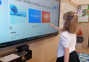 Uczniowie rozwiązują na tablicy multimedialnej zadania związane z wodą