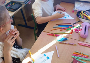 Uczniowie wykonują prace plastyczne, rysując sposoby oszczędzania wody.