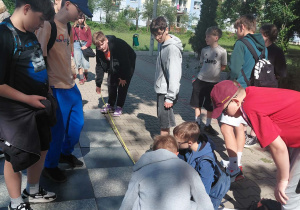 Uczniowie klas ósmych wykonują zadania matematyczne podczas gry terenowej