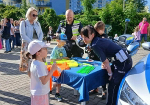 Grupa uczestników pikniku stoi przy stanowisku Policji.