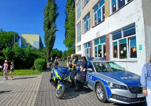 Policjanci, motocykl i samochód policyjny podczas pikniku w Szkole Podstawowej nr 137