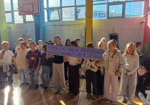 Uczniowie klasy 4d podczas apelu prezentują swoje hasło – „Przemoc to nie rozwiązanie, wszyscy mamy jedno zdanie”.